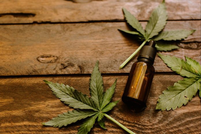 A bottle with cbd oil on brown wood table.