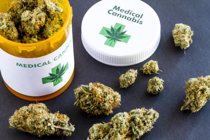 Medical marijuana buds in large prescription bottle with branded cap on black background