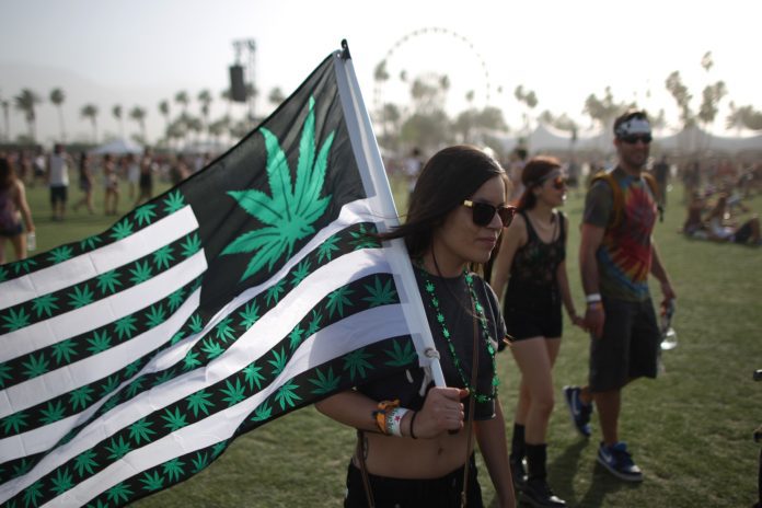 A woman carries a flag bearing marijuana symbols at the Coachella Valley Music & Arts Festival at the Empire Polo Club in Indio, California, April 12, 2014. The annual music festival, which runs for two consecutive three-day weekends, has grown to one of the largest music festival in the U.S. since it was founded in 1999. AFP PHOTO / David McNew (Photo credit should read DAVID MCNEW/AFP/Getty Images)